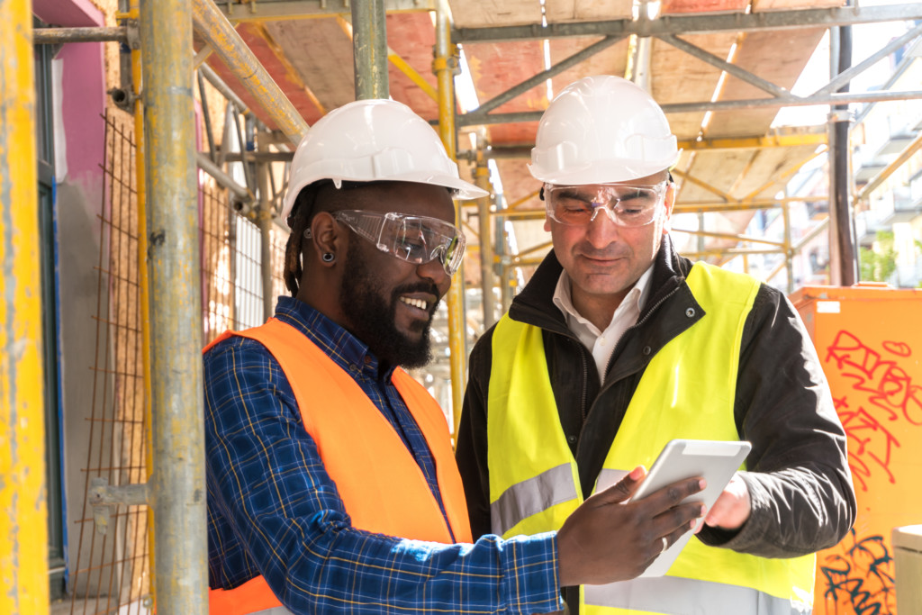Two construction workers looking over project plans in a tablet. 